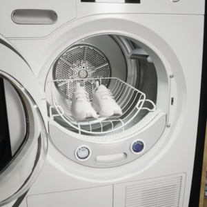 Sie sehen einen offenen Miele Trockner mit speziellem Trocknerkorb fuer Turnschuhe.